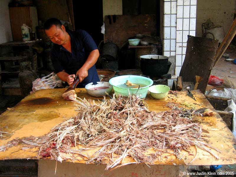 A friendly neighborhood butcher in a small town along the Yangtze River shows off the freshness of his goods.  Yes, folks, those are indeed freshly-plucked chicken feathers. 