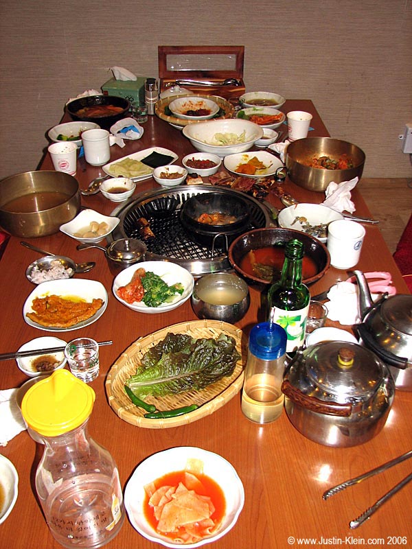 The table after a meal of Yakiniku. Count the number of plates. That's not even close to the number that we used during our four-person meal: the waiter was constantly coming to remove finished dishes and replace them with new tasty treats to tickle our taste buds.