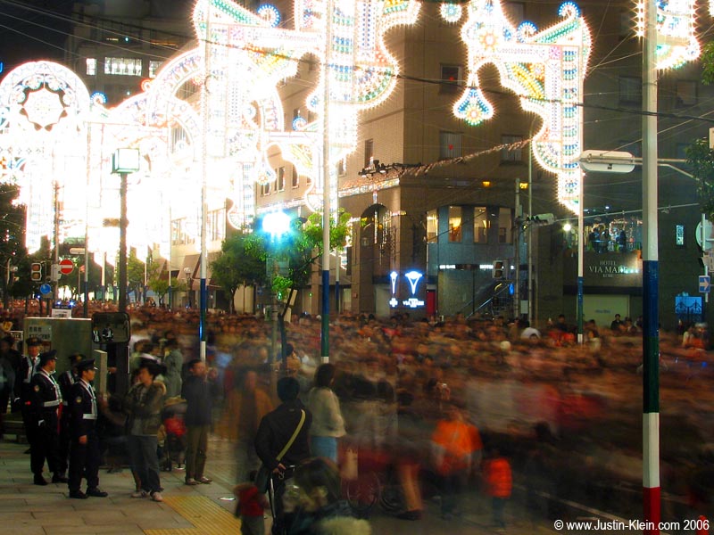 Crowds zoom by under the lights of Kobe's Luminarie Festival.