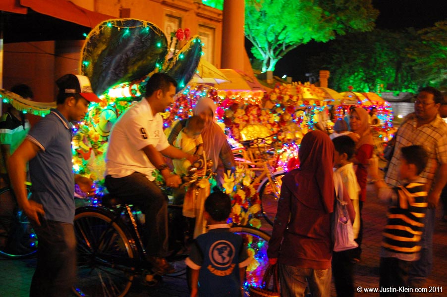 A family of tourists negotiating with a trishaw driver in Dutch Square, Melaka.